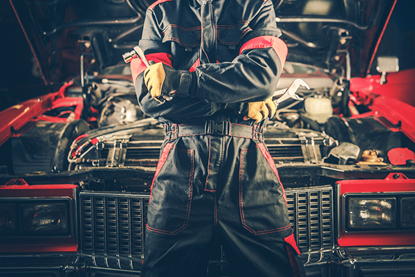 An image of a confident mechanic in front on a car he's working on